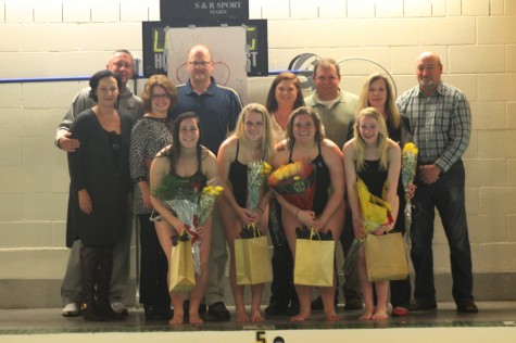 The four senior girls take a picture with their parents as they hold their bags and certificates. 
