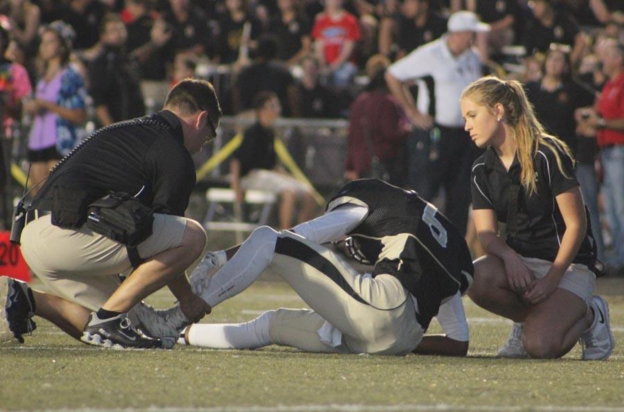 Athletic trainer Mike Atkinson helps wide receiver Antwan Banks (12) after he got injured in the first quarter. Banks did not play the rest of the game.