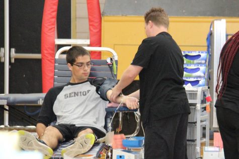 Staring down at his arm, Greg Davidson (12) watches the nurse draw his blood at the blood drive on Oct. 27.