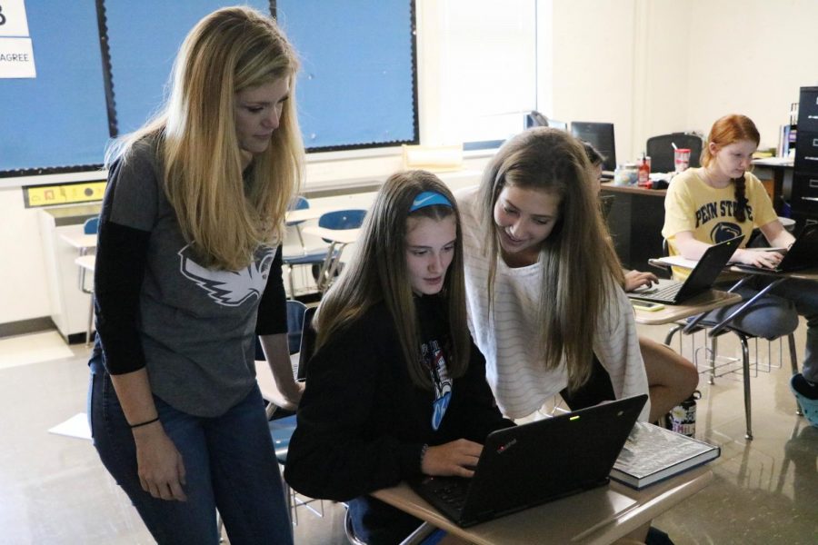 Mrs.Beck helps Brooke Seyer and Grace Bayer with Chromebook in her government class