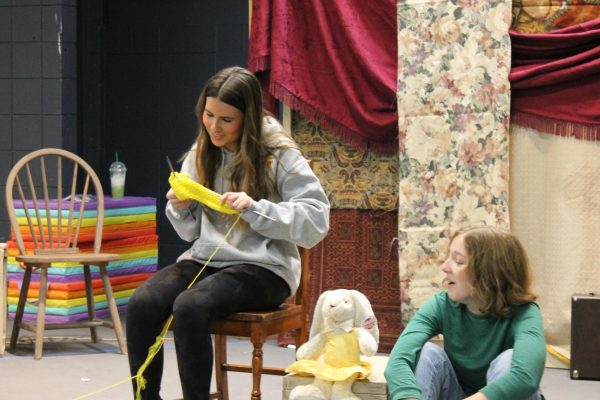 Macy Judd (12) and Delaney Murphy (12) Rehearses one of the scenes while Judd attempts to knit. Right now were working on cleaning. So we work chunk by chunk to make sure that its exactly where we want it to be transitions and things like that, Judd said. Judd and many of the other actors play multiple roles in this one-act play.