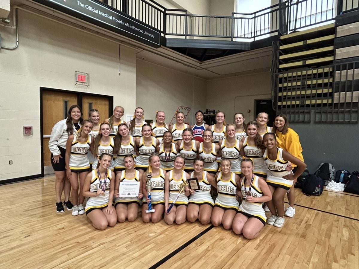Varsity cheer coach Cassidy Vuylsteke poses with her cheer team. "The most important part of cheer, I think, is just being a pillar of spirit for your school," Vuylsteke said. Vuylsteke was her third year coaching cheer. 